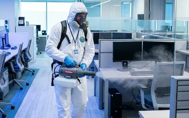 Técnico con buzo integral y equipo de nebulización ambiental