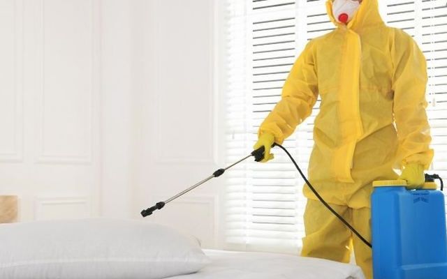 Técnico con buzo tratando una cama contra chinches